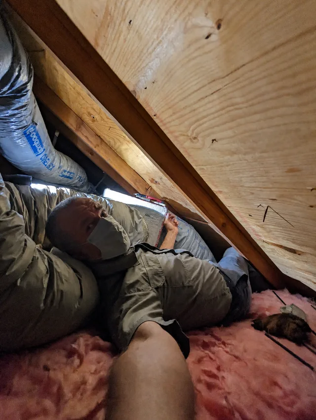 Dima working on HVAC ductwork in a tight attic.